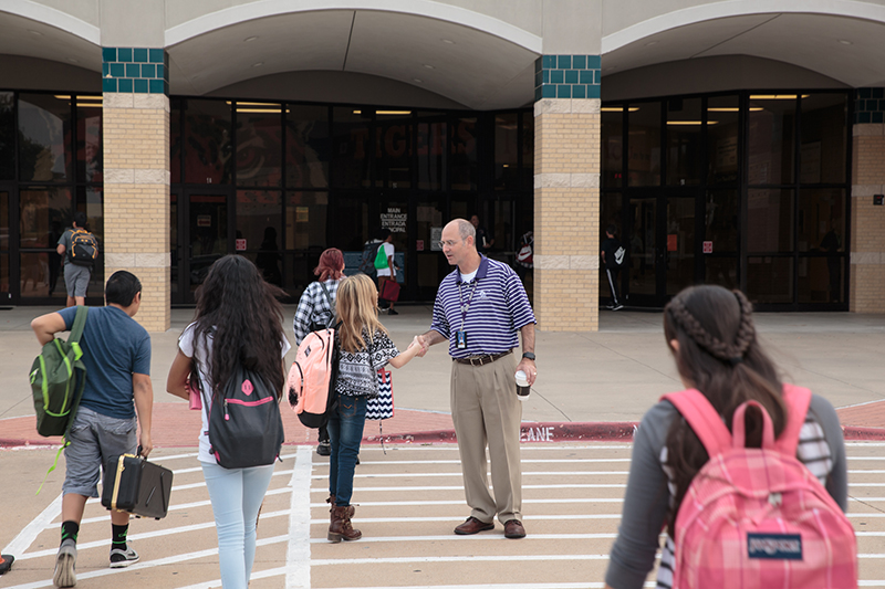 Mitch Curry shaking hands with a femail student as other students walk by in the crosswalk.