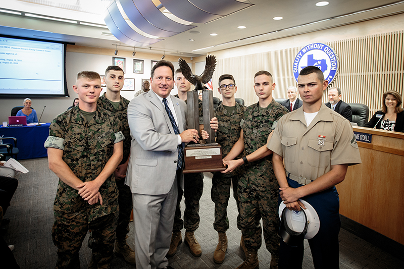 Group shot of McDaniel and cadet holding trophy surrounded by the rest of the cadet team