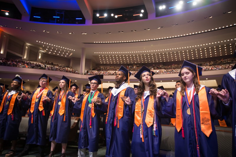 Graduates holding hands singing