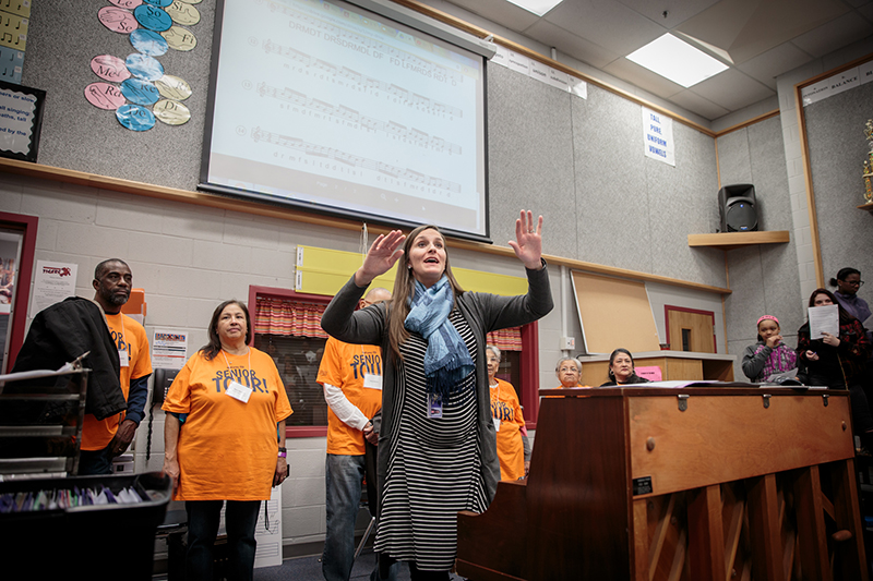 Teacher with hands raised directing choir