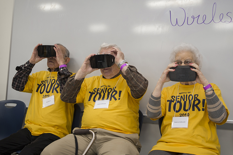 senior adults holding virtual reality goggles to their eyes