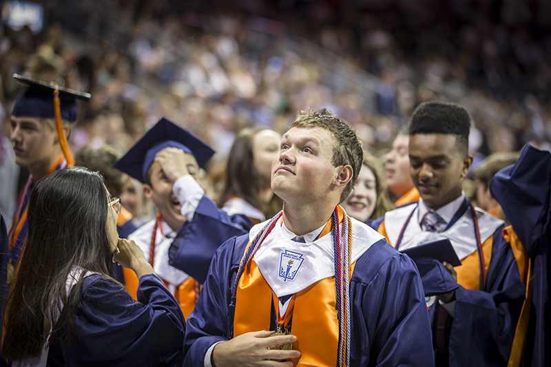 graduate looking up as others celebrate around him