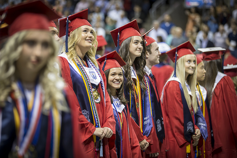 female graduates looking up toward boards