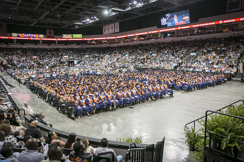 graduates seated in chairs on floor of the arena