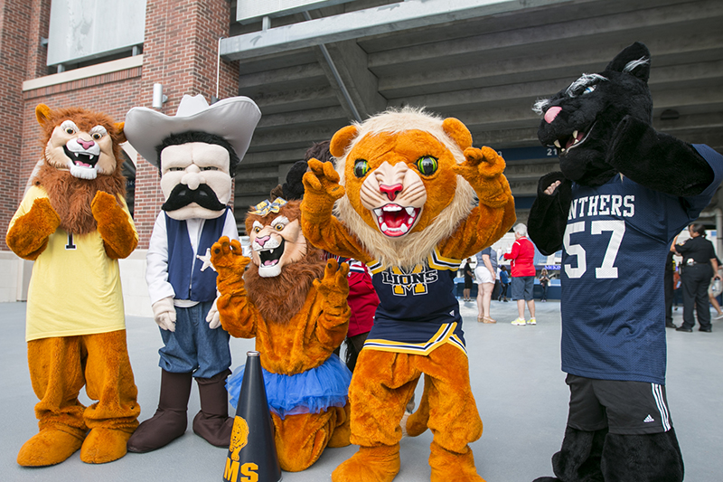 five mascots in a line cheering at camera