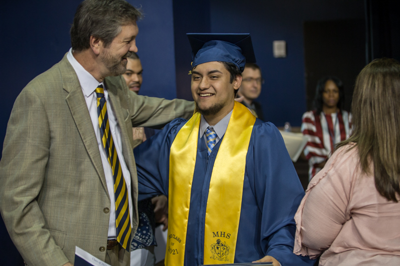 assistant principal tom wales congratulates a graduate as he heads back to seat