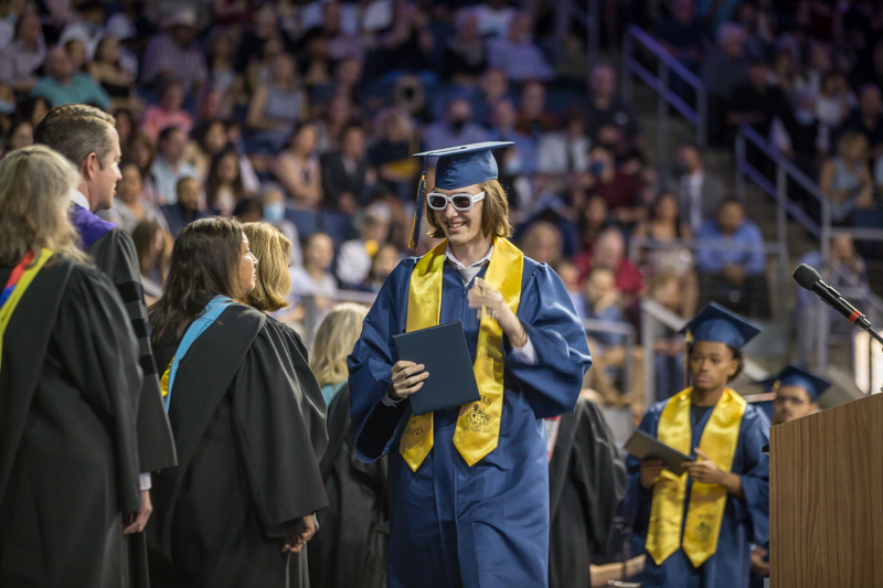 male student crossing stage with sunglasses