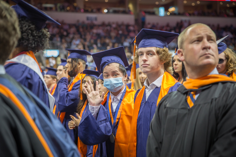 male graduate waving at camera