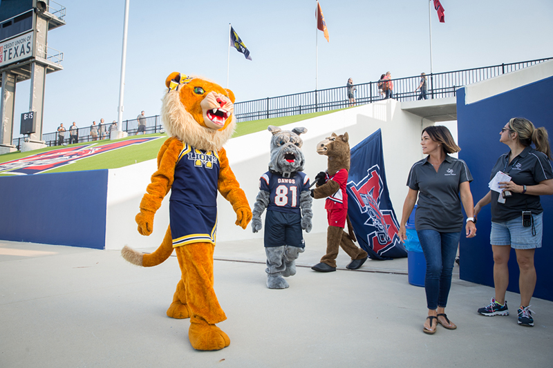 three MISD high school mascots walking into stadium
