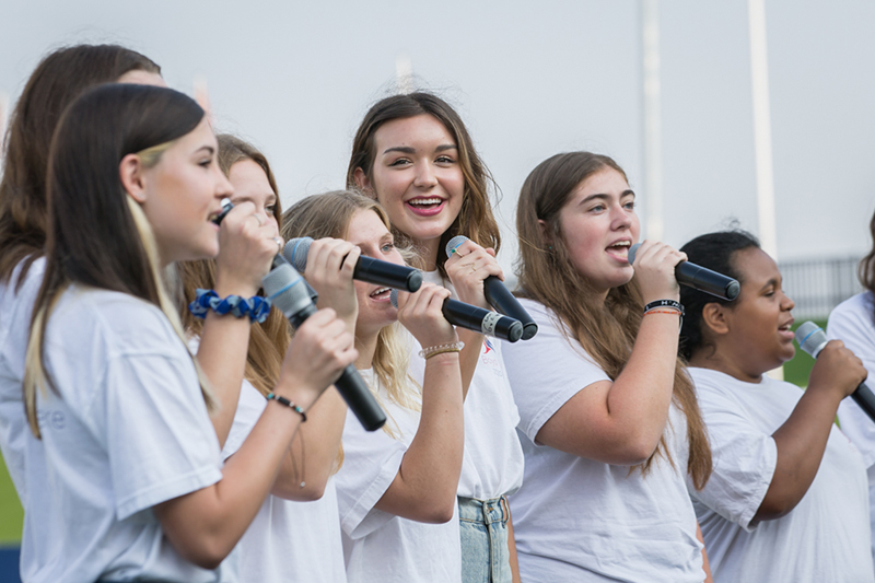 female choir performers singing holding microphones
