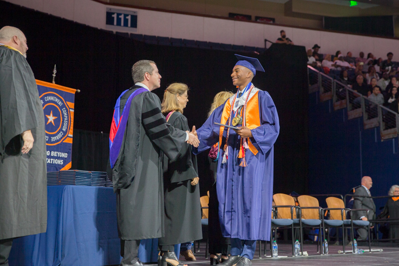 male grad onstage shaking hands