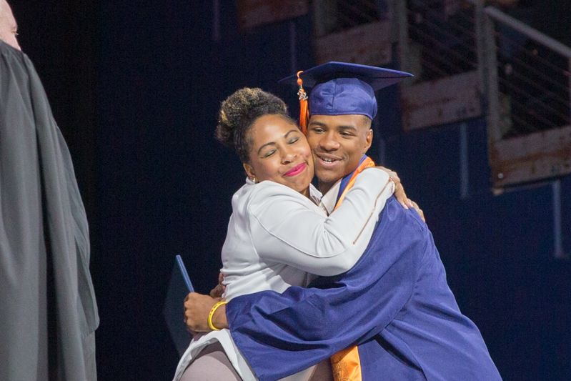 mom and son graduate hugging onstage
