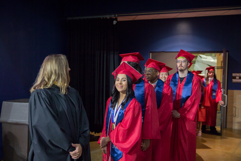 graduates in a line with female graduate smiling at camera