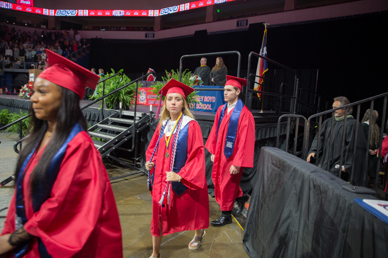 female graduate walking in a line and looking at camera