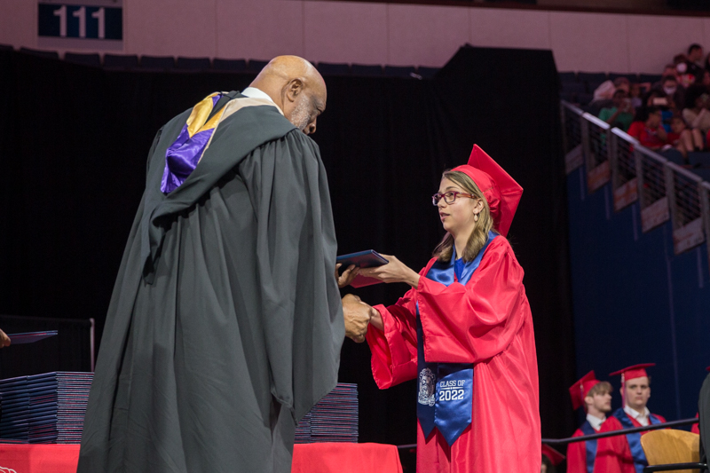 Board member Larry Jagours handing diploma to female student