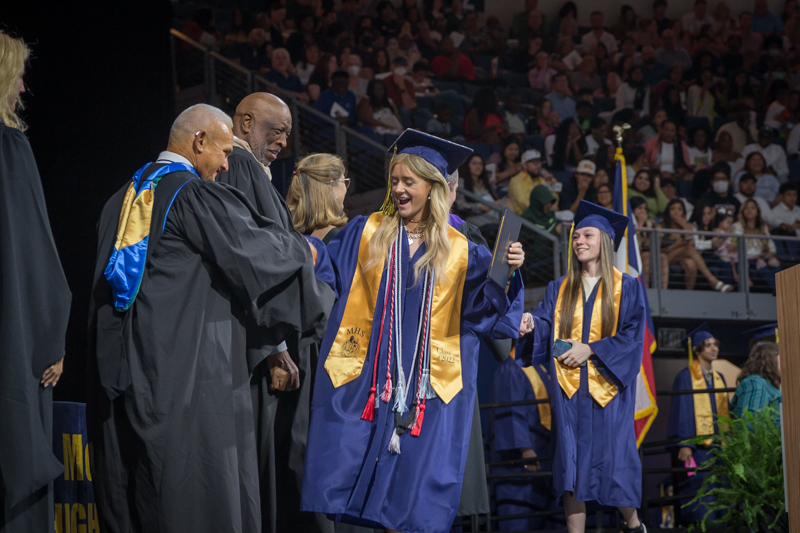 female graduate shaking hands with board in celebratory fashion
