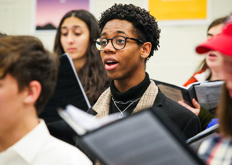 male high school choir student singing with group in class