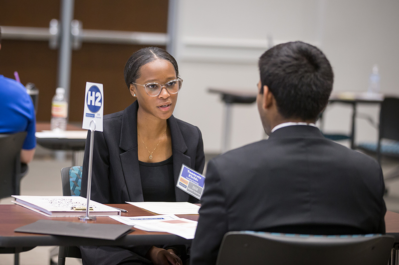 female student talking with a local business professional at a table