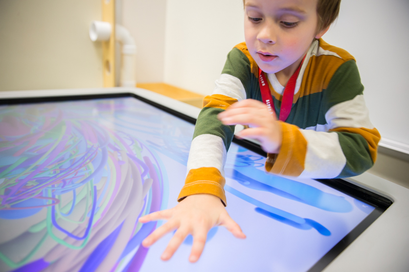 student creating art on a digital table with his hand