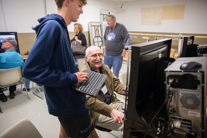 student with computer keyboard as senior adult looks on with a smile