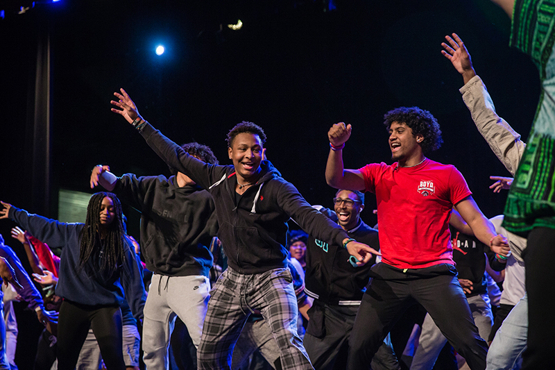 students with arms upraised, following dance and smiling