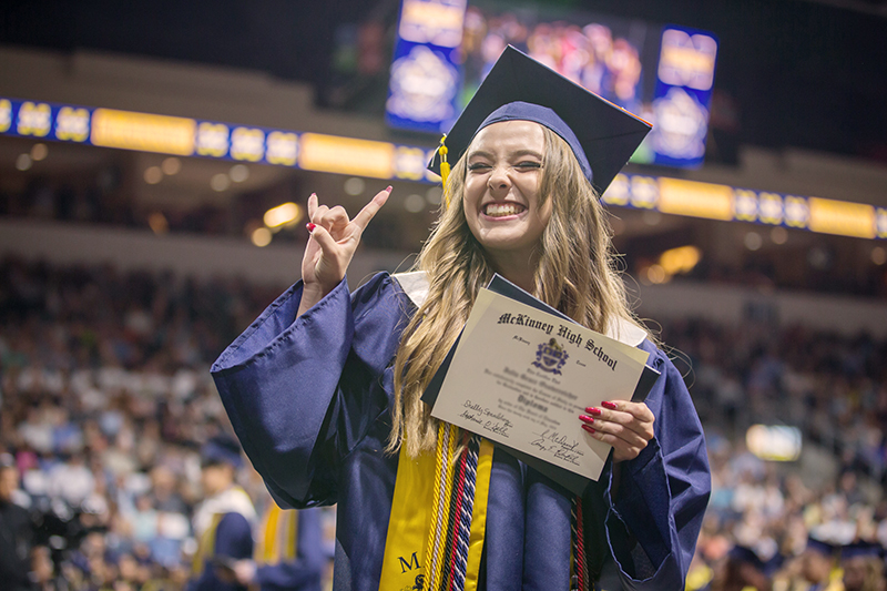 smiling girl with diploma making Texas Longhorns hand gesture 