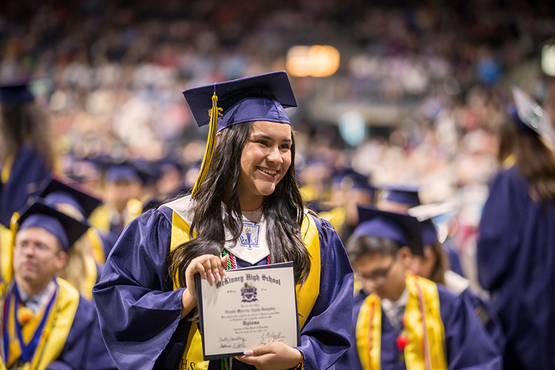 female graduate smiling with diploma for photo
