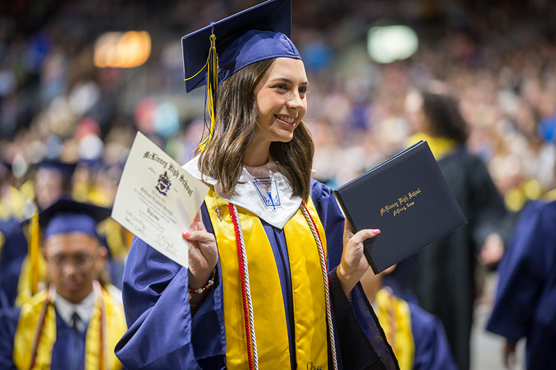 female graduate smiling for photo holding diploma