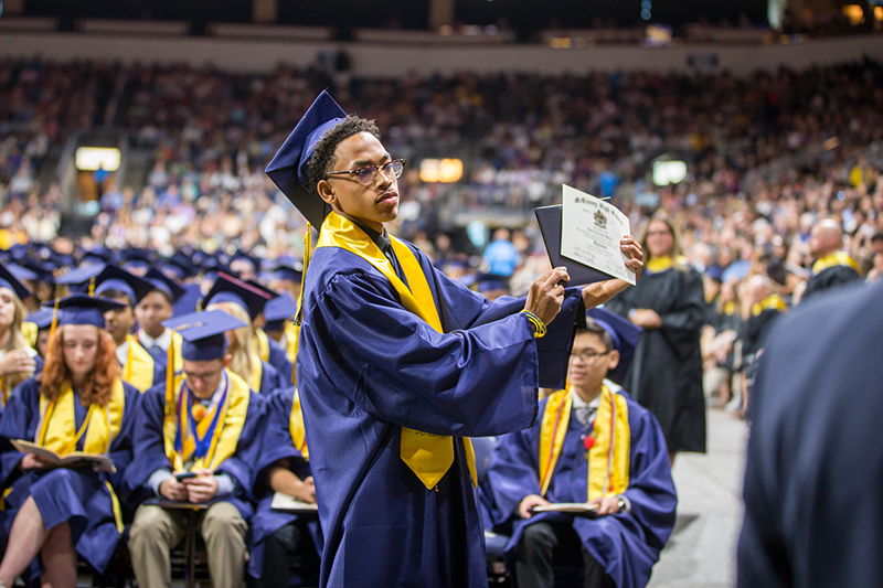 male student holding up diploma for a photo 