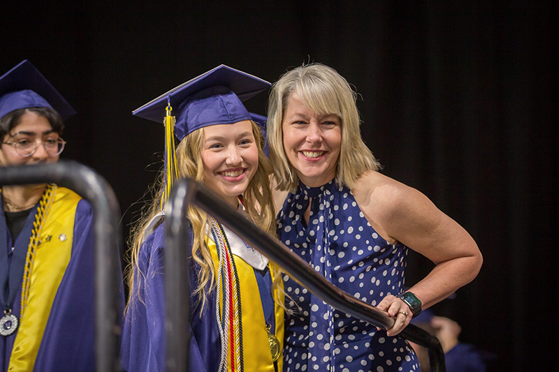 mother with daughter graduate smiling for a photo while waiting to go onstage