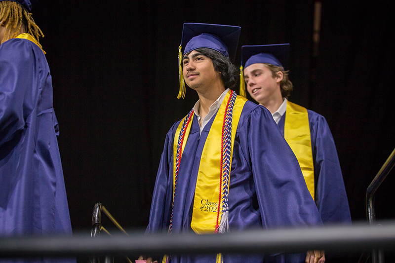 male graduate smiling while walking in line toward stage