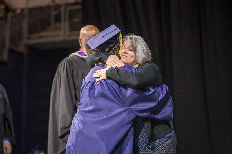 mom hugging graduate with smile on her face