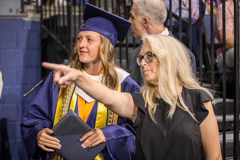 female staff member pointing direction for female graduate