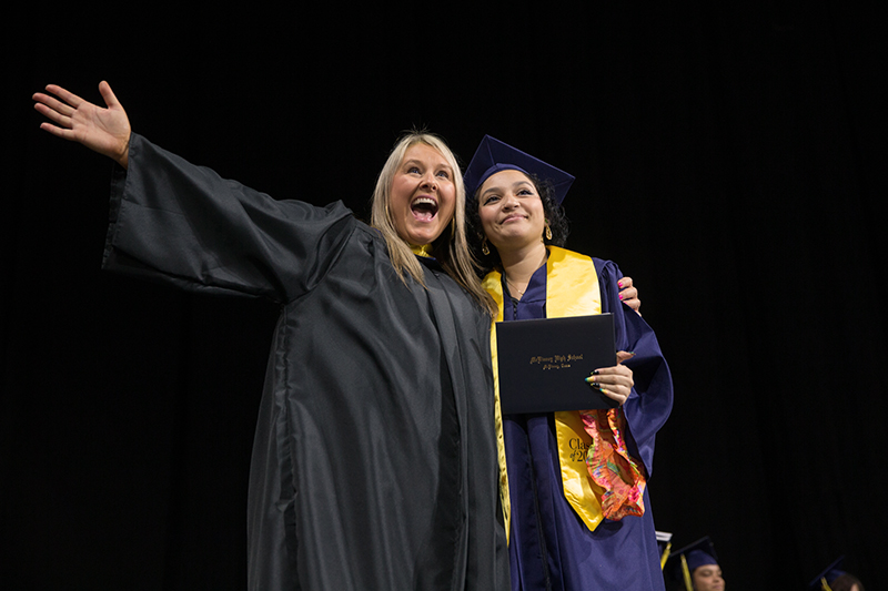 MHS principal Shelly Spaulding making wide arm gesture and smiling with final graduate 