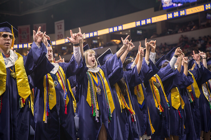 MHS graduates with fingers interlocked singing alma mater