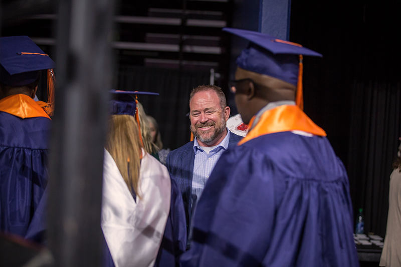 Assoc. Athletic Director Mike Fecci laughing with graduates in line