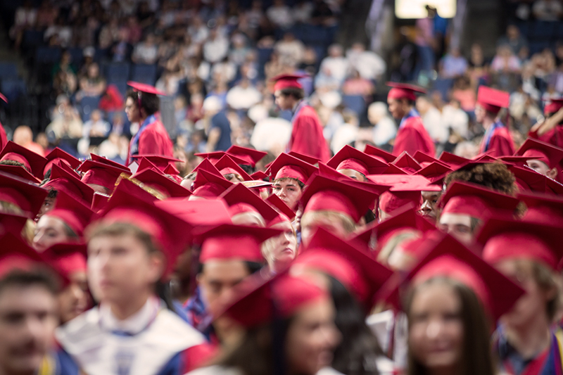view across the tops of Boyd graduates caps with one student face visible in the middle 