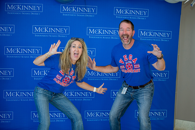 man and woman posing in humorous way for photo in front of blue backdrop