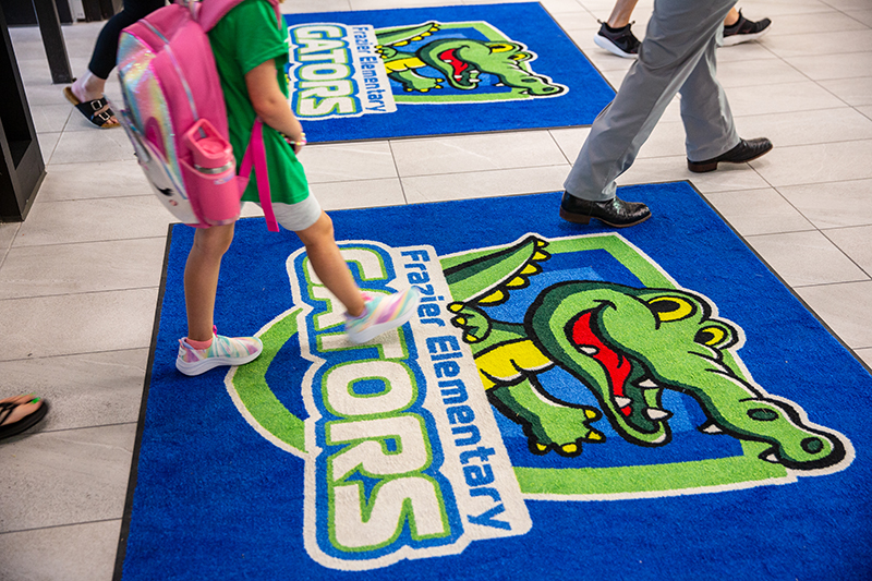 student feet walking across rug with Frazier logo