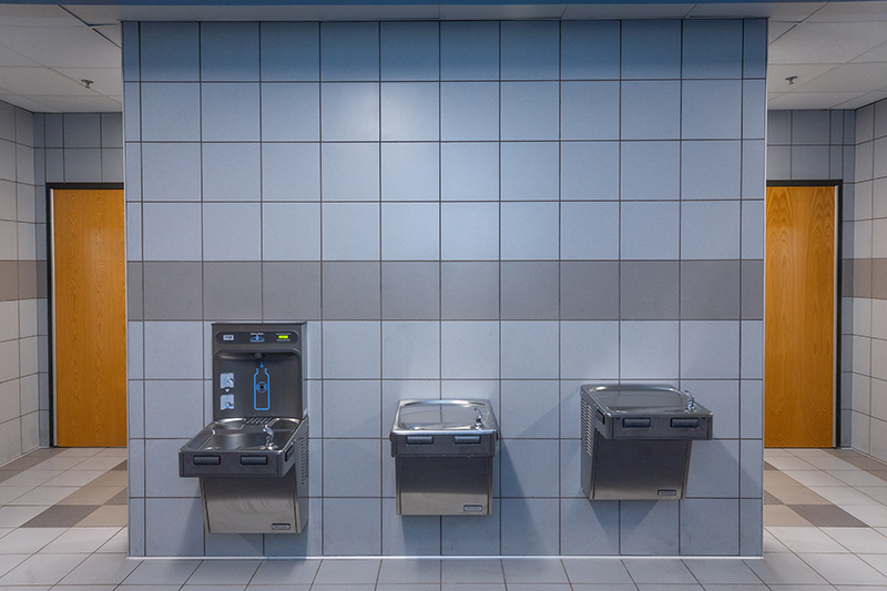 view of tile wall outside the bathrooms with waterfountains