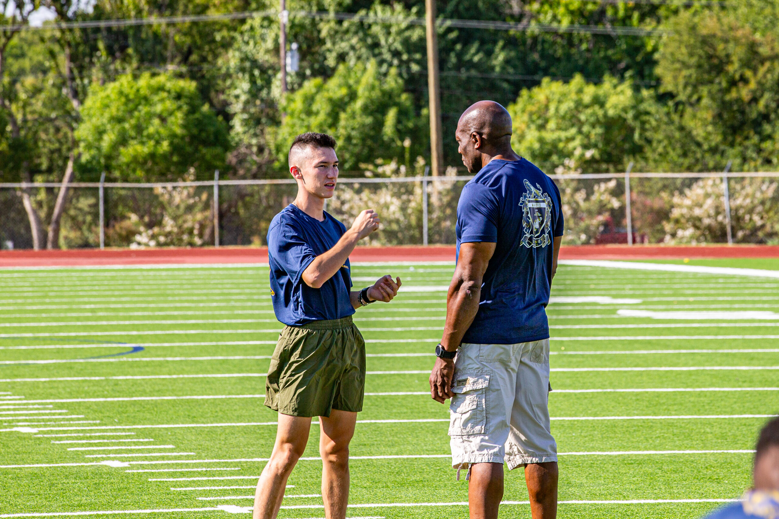 McPhatter and student talking on the football field durning physical fitness training