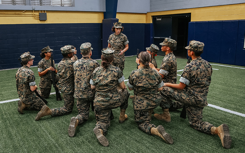 cadets kneeling in a group around cadet leader