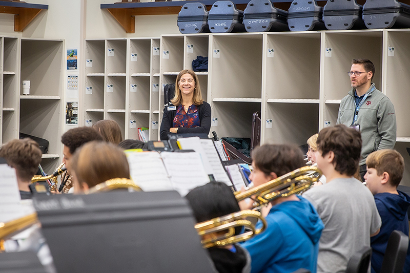 Odell smiling in the band hall as band plays a song