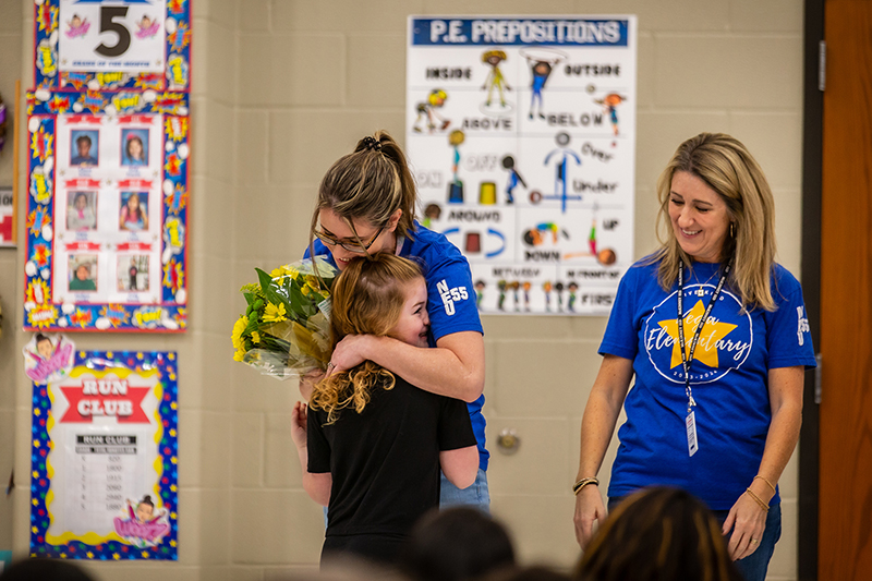 Vega teacher of the year Valerie Carpenter with flowers hugging student