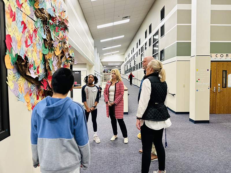 Dankel with group looking at display of student art in the hallway at Eddins