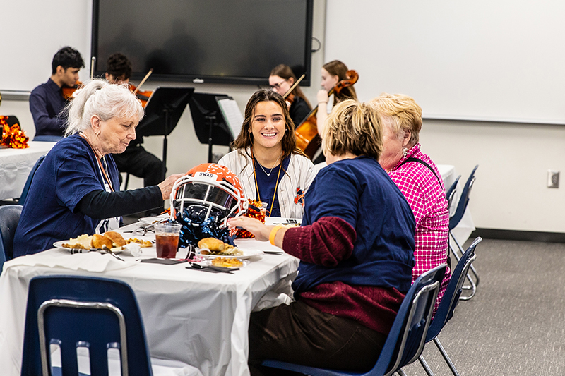female North student smiles as she talks with guests during lunch